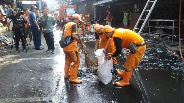 Petugas membersihkan sampah sisa kebakaran di lokasi.