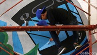 Aksi seorang seniman membuat mural.