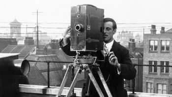 Seorang warga menggunakan kamera kinematograph dengan tripod yang terpasang di bawah kamera. Topical Press Agency/Hulton Archive/Getty Images.