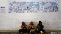 Warga bersantai di bawah mural yang telah selesai dibuat.