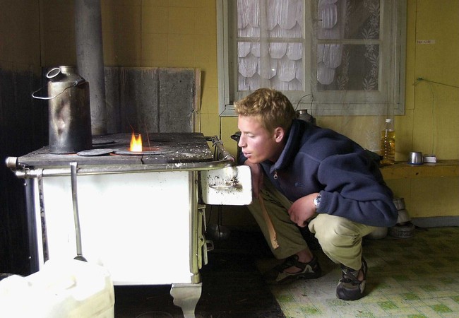 Hidup di desa terpencil berarti segala sesuatu dilakukan secara manual, termasuk urusan menyalakan kompor. Pangeran William tampak mencoba meniup sumbu kompor agar api menyala. (Foto: Toby Melville-Pool/Getty Images)