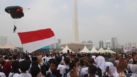 Sebelum mendarat di depan panggung, para penerjun payung terbang mengitari Monas. Ada pula penerjun payung yang membawa bendera Merah Putih, bendera TNI, serta bendera bertulisan Merajut Persatuan dalam Kebhinekaan dan Milennial Safety Road. 