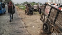 Seorang warga melintasi di depan tumpukan sampah di pinggir jalan Sunter.