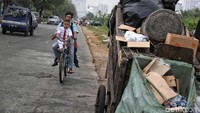 Seorang warga melintasi di depan tumpukan sampah di pinggir jalan Sunter.