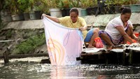 Seorang warga nampak membilas pakaiannya di kali yang berada di depan rumah.