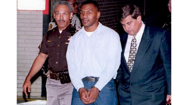 Mike Tyson (C), the former world heavyweight boxing champion, leaves Marion County Courthouse in Indianapolis, Indiana, flanked by his associate attorney Jim Voyles (R) and a police officer (L), after a 13 June 1994 sentence-reduction hearing. Tyson, who was convicted of rape, is scheduled to be released 25 March. (COLOR KEY: Tyson wears blue trousers.) AFP PHOTO (Photo by EUGENE GARCIA / AFP FILES / AFP)