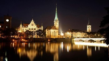 Cahaya lampu yang terefleksi dari sungai di Kota Zurich, Swiss, membuat pemandangan kota itu semakin menawan di malam hari. Mike Hewitt/Getty Images.