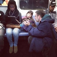 Ketika isi gerbong kereta sedang padat-padatnya, seorang ayah rela duduk jongkok agar tetap bisa membacakan buku untuk sang putri. (Foto: Dok. BrightSide)