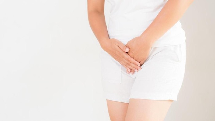 Young woman in yellow short dress standing with her hands between legs, needs a restroom, isolated for white background. Womens health, gynecology.