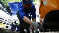 Petugas memasukan alat uji emisi ke knalpot kendaraan.