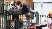 Meski membawa barang cukup banyak, dua warga ini nekat melompati pagar.