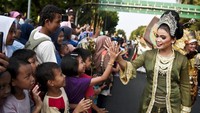 Peserta parade menyapa warga yang menonton di pinggir jalan. 