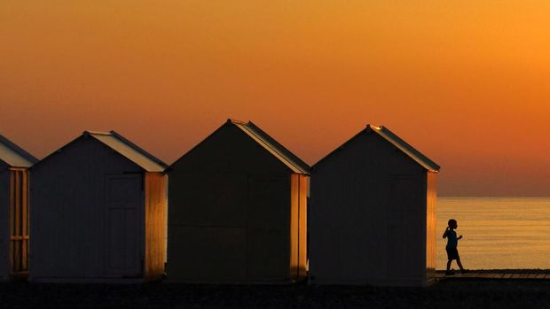 A child walks beside beach cabins on a pebbled beach, during sunset as a heatwave hits France, in Cayeux-sur-Mer, France, June 29, 2019. REUTERS/Pascal Rossignol     TPX IMAGES OF THE DAY