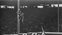 Potret Evel Knievel menunjukkan kemampuannya mengendarai motor Harley-Davidson dengan melompat setinggi 140 kaki dan melewati 13 bus yang terparkir berjejer di bawahnya. Foto ini diambil pada tanggal 26 Mei 1975. David Ashdown/Keystone/Getty Images.