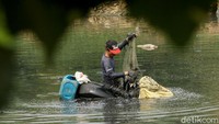 Seorang warga memanfaatkan air Sungai Ciliwung di Banjir Kanal Barat, yang mulai surut untuk memancing ikan, Selasa (2/7/2019).