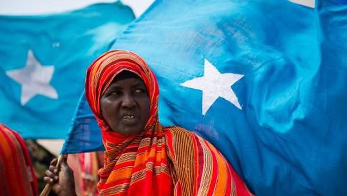 A woman stands holding the Somali flag as she waits to welcome back Somali Prime Minister Abdiweli Mohamed Ali at Mogadishus Aden Adde International Airport on March 11, 2012. The Somali Prime Minister was visiting Kenya on March 10 to hold talks with government officials about how the two countries could fight Al-Qaeda linked militants of the Somali group Al-Shabab, pledging his governments commitment to working with the Kenyan Defense Forces.    AFP PHOTO/ PHIL MOORE (Photo by PHIL MOORE / AFP)