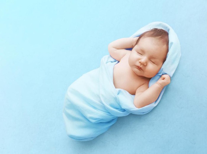 Newborn baby sleeps on blue background. Childs portrait.
