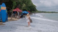 Seorang wisatawan tampak menerjang gelombang pasang di Pantai Kuta, Bali, Jumat (5/7/2019).