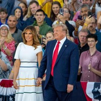Melania Trump muncul dalam balutan gaun putih Carolina Herrera dan sepasang heels Louboutin berwarna fuchsia. Gaun seharga Rp 17 juta itu dipermanis dengan detail pita di bahu dan garis-garis pada bagian rok. (Foto: Getty Images)