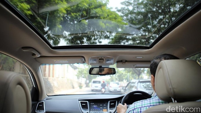 Pengendara mengendarai mobil yang memiliki Panoramic Sunroof