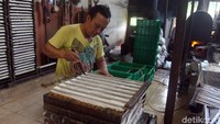 Seorang pekerja sedang sibuk memotong tahu.