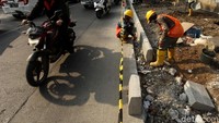 Para pekerja mengerjakan proyek trotoar saat arus lalu lintas di kawasan tersebut ramai lancar.