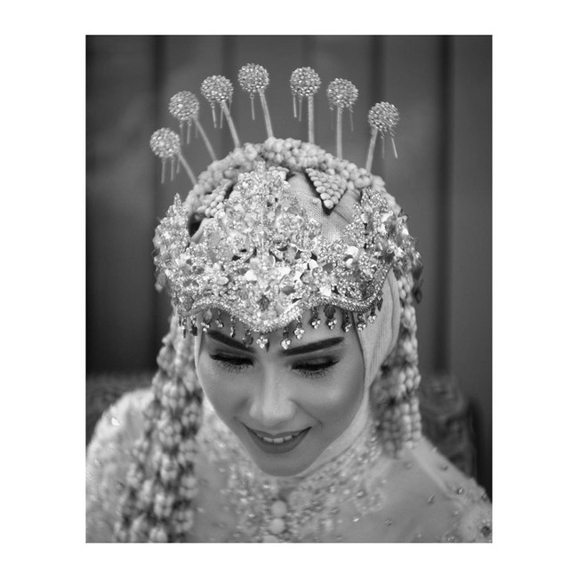 Hijab tak menjadi penghalang untuk tetap memesona dengan siger di hari pernikahan untuk pengantin yang menerapkan adat Sunda di hari bahagianya. Seperti penampilan kakak Iqbaal Ramadhan ini. Tampak siger dan bunga melati menyatu sebagai hiasan hijabnya. Foto: Instagram @iqbaal.e, Instagram @danikadaviscamakeup