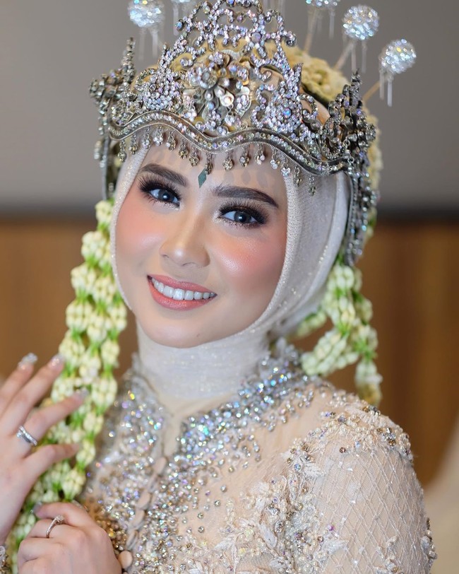 Seperti inilah perpaduan hijab dan siger ala kakak Iqbaal Ramadhan di hari pernikahannya. Penampilan wanita yang berprofesi sebagai dokter gigi ini semakin memesona berkat riasan flawless dari makeup artist Danika Davisca. Foto: Instagram @iqbaal.e, Instagram @danikadaviscamakeup