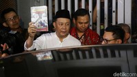 Syafruddin keluar rutan KPK sambil menunjukkan buku Bencana BLBI.