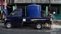 Warga membeli air bersih dari pedagang yang datang ke pemukiman mereka menggunakan tandon-tandon air.
