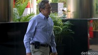 Glenn nampak mengenakan kemeja lengan panjang berwarna cerah saat tiba di gedung KPK.