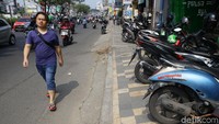 Seorang pejalan kaki melintas di kawasan Margonda, Depok, Jawa Barat, Rabu (10/7/2019). Pejalan kaki tersebut berjalan di jalan raya karena trotoar di sebelah sisinya justru digunakan untuk parkir kendaraan roda dua.