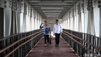 Sejumlah jurnalis melintas di atas skybridge di Stasiun LRT Velodrome,  Jakarta Timur, Kamis (11/7).