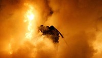 Petugas nekat mendekati mobil yang terbakar demi lenyapnya api yang membara di Francis. (Reuters).