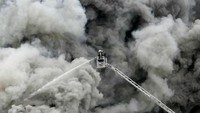 Petugas pemadam kebakaran terkepung asap saat memadamkan kebakaran di gudang suku cadang Mercedes-Benz di Jerman. (Reuters).