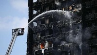 Petugas pemadam kebakaran menyiramkan air ke Grenfell Tower setinggi 24 lantai di London Barat yang terbakar pada 2017 lalu. (Getty Images).