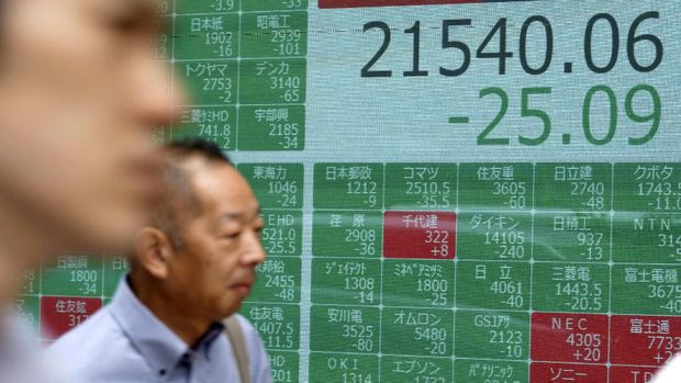 Japan Financial Markets People walk past an electronic stock board showing Japan's Nikkei 225 index at a securities firm in Tokyo Wednesday, July 10, 2019. Asian shares were mostly higher Wednesday in cautious trading ahead of closely watched congressional testimony by the U.S. Federal Reserve chairman. (AP Photo/Eugene Hoshiko)