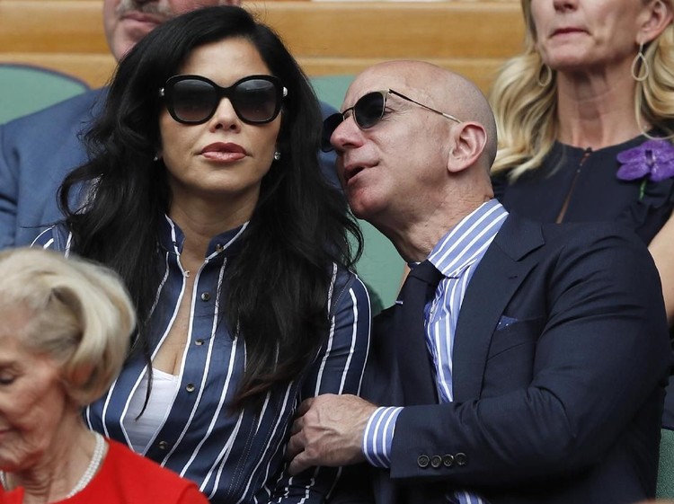 Amazon Founder and CEO Jeff Bezos, right, and Lauren Sanchez, watch Serbias Novak Djokovic play Switzerlands Roger Federer during the mens singles final match of the Wimbledon Tennis Championships in London, Sunday, July 14, 2019. (Adrian Dennis/Pool Photo via AP)