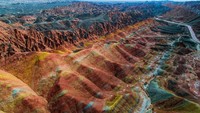 Di Tiongkok ada pegunungan pelangi yang bernama Danxia, taman bumi nasional Zhangye. Lokasi dimana banyak fotografer berimajinasi dengan garis-garis oranye, putih, kuning, dan cokelatnya yang berasal dari kandungan batu pasir dan mineral. Photons_in_action/Getty Images.