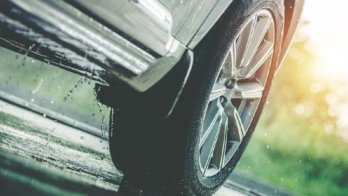 Car Driving in the Rain. Modern Rain Summer Season Tires on the Wet Pavement. Closeup Aquaplaning Photo.