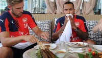 Makan bareng Theo Walcott, kali ini Ramsey mencicip sate dan hidangan berbahan daging lain di Singapura. Foto: Getty Image  
