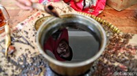 Perajin mencelupkan kanting ke dalam wajan berisi malam. Setelah itu canting digoreskan ke kain.