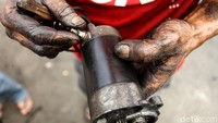 Seorang montir memperlihatkan kompenen dari bajaj.