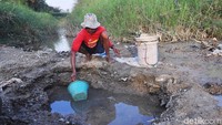 Warga mendatangi sumur-sumur belik yang baru saja digali di dasar sungai mengering untuk mendapatkan air yang masih tersisa.