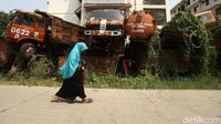 Seorang warga melintas di depan tumpukan truk di kawasan Cengkareng, Jakarta Barat.