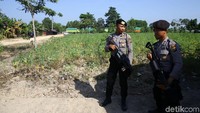 Polisi berjaga dengan membawa senjata api laras panjang.