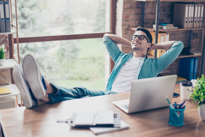 Happy calm smiling man having a rest after solving all the tasks at work
