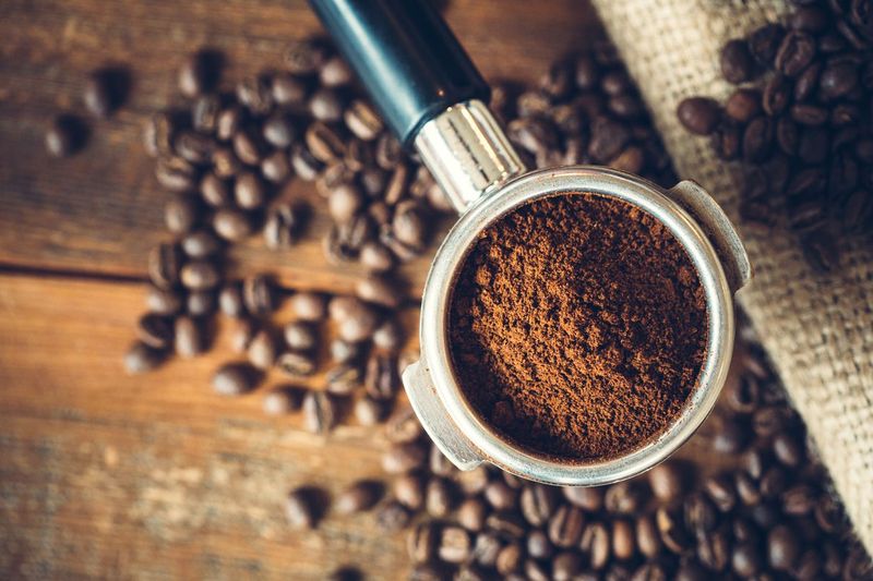 Fresh hot coffee being poured into a cup from a stainless steel french press in a trendy cafe