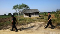 Dua anggota Brimob bersenjata lengkap berkeliling menelusuri sekitar lokasi kejadian perkara.