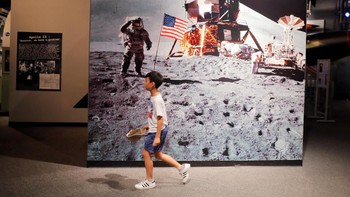 Seorang anak melewati gambar besar yang merekam pendaratan di Bulan. Foto: Getty Images